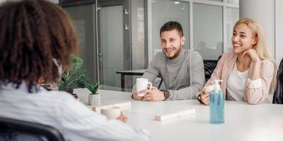 Modern office, coffee break and health protection. Multiracial employees have relax in restroom with antiseptic, cups and protective partition at quarantine, free space photo