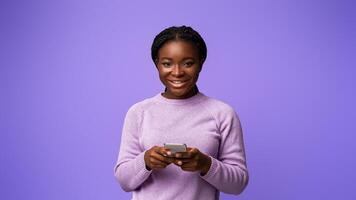 Mobile Offer. Positive Black Millennial Female Posing With Smartphone In Hands On Purple Background, Using New App Or Browsing Internet, Enjoying Modern Technologies And Communication, Copy Space photo