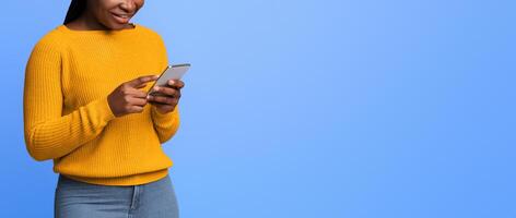 Mobile Communication. Unrecognizable Black Woman Using Smartphone, Texting With Friends Or Browsing Internet, Standing With Cellphone In Hands Over Purple Background In Studio, Cropped Image, Panorama photo