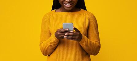 Smiling African American Lady Holding Smartphone, Texting With Friends On Yellow Background, Cheerful Black Female Using Cellphone, Enjoying Modern Technologies And Mobile Communication, Copy Space photo