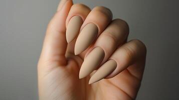 This Close-up of soft beige almond-shaped nails with a matte finish, showcasing nail care techniques. photo