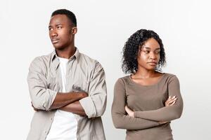 Break up, troubles, misunderstanding in relationships or marriage. Upset african-american man and woman standing next to each other with arms crossed after fight, gray studio background photo