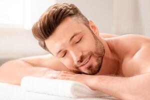 Relaxed middle aged man attending spa salon on weekend, lying on his belly on massage table, closeup. Handsome bearded man resting with closed eyes while waiting for relaxing back massage photo
