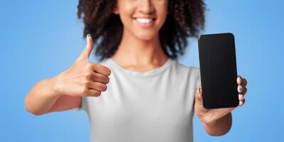Site review, best buy, blogger advice and ad. Excited smiling generation z african american female show blank screen of smartphone to camera and thumb up gesture, isolated on violet background photo