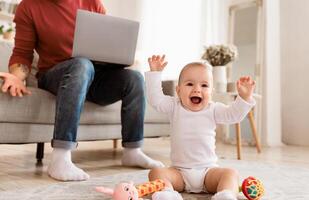 Baby Toddler Shouting Bothering Father While He Working On Laptop Sitting On Sofa At Home. Single Parenting And Paternity Leave Problems, Freelance, Distant Work Difficulties. Cropped, Selective Focus photo