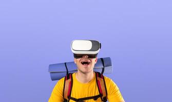 Virtual travel. Happy young man with VR headset and joystick on traveling adventure in cyberspace over blue studio background. Excited guy having tour or journey in augmented reality photo