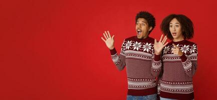 Wow, it is amazing, dream come true, about best gift. Happy and shocked african american family looking at empty space, young woman with open mouth points finger, man expresses emotions, studio shot photo