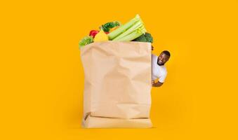 A customer joyfully engages with a large paper bag full of fresh vegetables and fruits. The vibrant background highlights the shift towards online shopping and home delivery services in daily life. photo