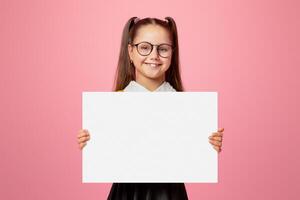 Back to school sales. Cheerful child schoolgirl in uniform and glasses holds sign with empty space, isolated on pink background, studio shoot photo