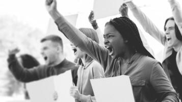 Side view of furious multiethnic millennial protestors with blank placards chanting slogands next to government building on the street, striking against 2021 lockdown restrictions, closeup photo