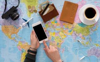 Travel planning online concept. Searching or booking tickets online, preparation for summer vacation, tourist stuff and blank smartphone on map background, top view photo