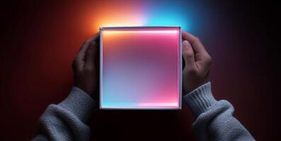 A person holds an open delivery box with vibrant inner illumination. The soft glow creates a contrasting effect against the dark background. photo