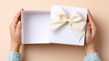 Hands gently open a white delivery box adorned with a soft bow. The background is simple, highlighting the box's elegant design and the anticipation of its contents. photo