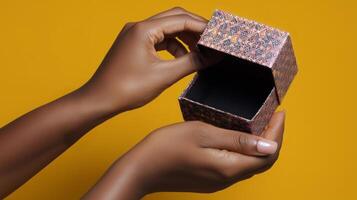 A pair of hands gently open a decorative box against a bright yellow background. The box features intricate patterns, suggesting a delicate and artistic design, inviting curiosity about its contents. photo