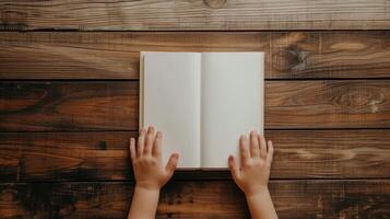 Hands holding open book on wooden table photo