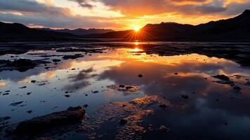 The sun rises over a mountain range and reflects in a lake video