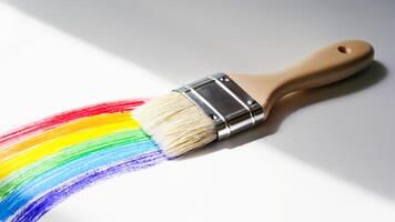 Paint brush creating vibrant rainbow stroke on white surface, symbolizing creativity, diversity, and expression. Perfect for artistic concepts, LGBTQ themes, and colorful design visuals photo