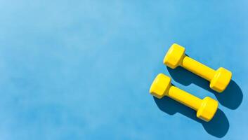 Yellow dumbbells on textured blue background photo