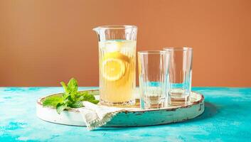 Refreshing homemade lemonade with lemon slices in glass pitcher with empty glasses photo