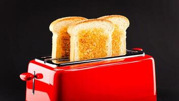 Retro red toaster with slices of toasted bread popping up on black background photo