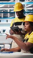 Vertical Black employees analyzing production line solar panels in the photovoltaics factory, analyzing data. Manufacturing plant engineers reading documentation files to troubleshoot errors. Camera B. video