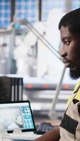 Vertical PC based solar technician reviews automation data in production factory, manufacturing industry focused on renewable energy. Worker tracks solar panels and machine performance. Camera A. video