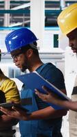 Vertical Group of black employees at the solar panels factory reviewing data on devices and documents. Photovoltaics facility engineers working on innovative solar cells design prototype. Camera A. video