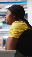 Vertical African american engineer analyzes energy consumption software in solar factory, uses PC program to enhance solar cell production and reduce faults in automated machinery systems. Camera A. video