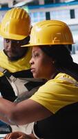 Vertical African american workers checking up on manufacturing equipment in solar panel factory, reading documentation files. Team of engineers in industrial facility inspecting production process. Camera A. video