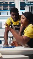 Vertical Team of black engineers finetuning the manufacturing on solar panels at the factory, doing quality control for the production line. Experts working on alternative energy industry. Camera A. video