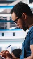 Vertical Portrait of engineer in photovoltaics factory reviewing paperwork to diagnose malfunctioning systems. Solar panels plant worker reading inspection data files to reduce downtime. Camera A. video