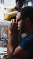 Vertical African american wheelchair user working in solar panel factory, optimizing systems for renewable energy. Engineer examines robot arms automation in a disability friendly power plant. Camera A. video