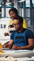 Vertical Technicians in photovoltaics factory reviewing solar panels assembly lines, reading industrial guidelines and ensuring seamless production. Black team optimizing the solar cell activity. Camera B. video