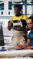 Vertical Colleagues troubleshooting solar equipment from computer station in a sustainable industrial factory. Black engineering team handles CAD software adjustments for production line. Camera B. video