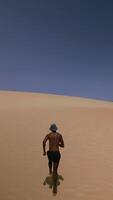 Drone View of Athletic Black Man Running on Fuerteventura Dunes in Swimsuit and Fisher Hat. video