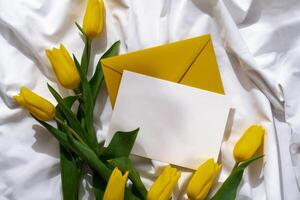 Bouquet of yellow tulips in craft paper bag on messy bed with white empty copy space postcard template. Romantic morning scene. Greeting card Holiday flowers springtime atmosphere photo