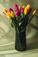 Multicolored fresh tulips in vase in green background with trendy deep shadows. Spring flowers in yellow and violet colors. Postcard wallpaper design Copy space photo