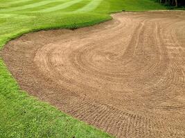Golf Course Sand Pit Bunkers, green grass surrounding beautiful sand holes is one of the most challenging obstacles for golfers and adds to the beauty of the golf course. photo