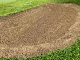 Golf Course Sand Pit Bunkers, green grass surrounding the beautiful sand holes is one of the most challenging obstacles for golfers and adds to the beauty of the golf course photo