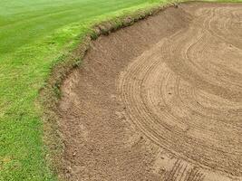 Golf Course Sand Pit Bunkers, green grass surrounding the beautiful sand holes one of the most challenging obstacles for golfers and adds to the beauty of the golf course. photo