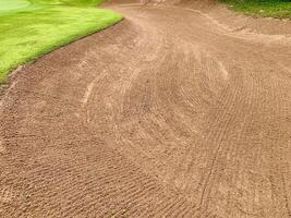Golf Course Sand Pit Bunkers, green grass surrounding the beautiful sand holes is one of the most challenging obstacles for golfers and adds beauty of the golf course. photo