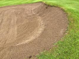 Golf Course Sand Pit Bunkers, green grass surrounding the beautiful sand holes is one the most challenging obstacles for golfers and adds to the beauty of the golf course. photo