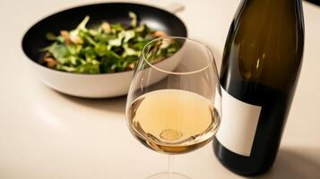 Fresh salad with white wine glass and bottle on a dining table setting at home photo