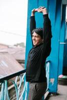 Stretching man expressing strain, outside on old building balcony photo