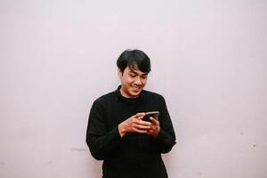 Contented asian man interacting with cellphone against light background photo