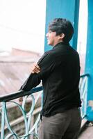 Smiling young man looks over the city from an ornate balcony photo
