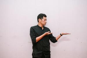 Pensive man presenting or displaying product on empty space photo