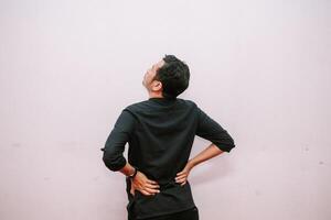 Man feeling lower back pain and looking up towards a blank background photo