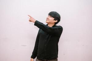 Young man pointing to something up above on clean isolated backdrop photo