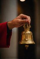 Close-up of hand ringing traditional brass bell in a temple setting photo
